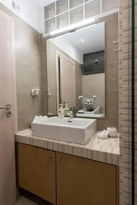 a bathroom with a sink and a large mirror at Urban Maisons in Athens