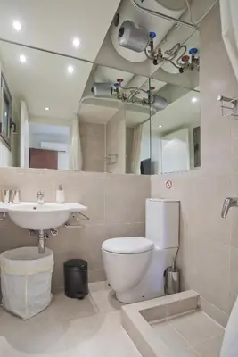 a bathroom with a toilet and a sink and a mirror at Cozy and modern studio Vouliagmeni Steps to Beach in Athens