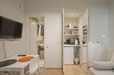 a living room with a table and a tv in a room at Cozy and modern studio Vouliagmeni Steps to Beach in Athens
