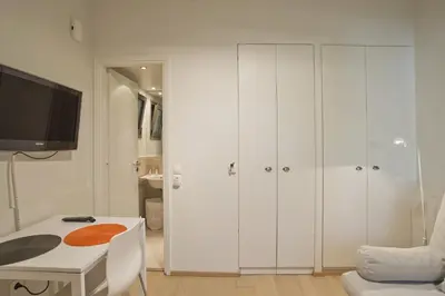 a room with white cabinets and a table and a tv at Cozy and modern studio Vouliagmeni Steps to Beach in Athens