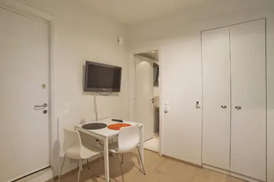 a white room with a table and chairs and a tv at Cozy and modern studio Vouliagmeni Steps to Beach in Athens