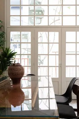 a glass table with a vase on it in front of windows at Vintage Acropolis Retreat Charming 3-Bdrm in Koukaki in Athens