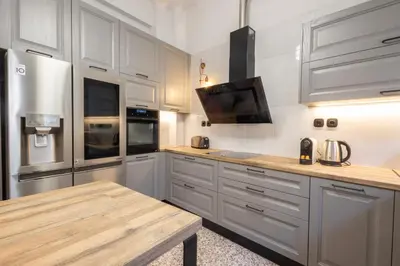 a kitchen with white cabinets and a wooden table at Acropolis View Rooftop Garden & Jacuzzi in Athens