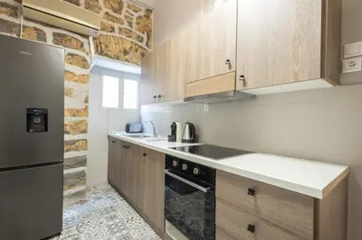 a kitchen with wooden cabinets and a stainless steel refrigerator at Acropolis View Rooftop Garden & Jacuzzi in Athens
