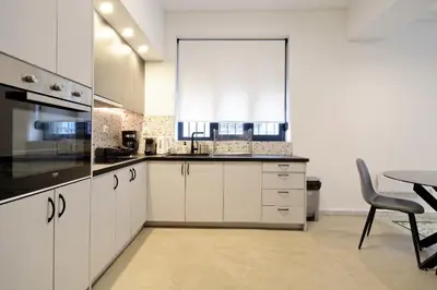 a kitchen with white cabinets and a table with a chair at Modern Corner Apartment in Central Athens, Pagrati in Athens