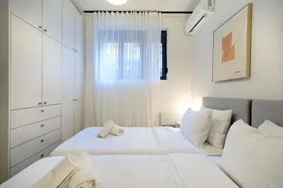 a white bedroom with two beds and a window at Modern Corner Apartment in Central Athens, Pagrati in Athens