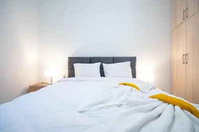 a bed with white sheets and yellow blankets at Odysseas Palace in Athens in Athens