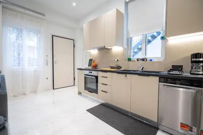 a kitchen with white cabinets and a large window at Odysseas Palace in Athens in Athens