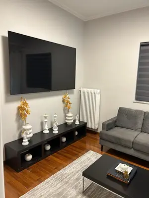 a living room with a couch and a tv on the wall at comfort in Athens