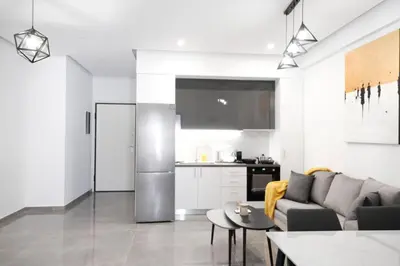 a living room with a couch and a kitchen at Cozy Home With Cooking in Piraeus