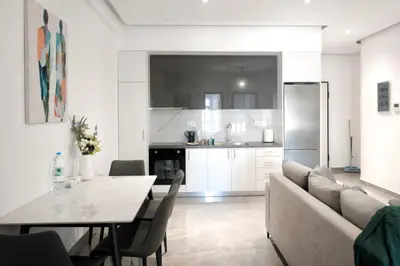 a kitchen and living room with a table and a couch at Cozy Home With Cooking in Piraeus