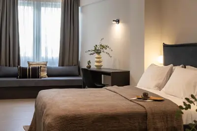 a bedroom with a bed and a couch and a window at Celestial Athens Suites at Praxitelous in Athens