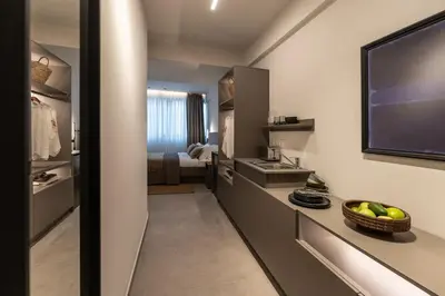 a room with a kitchen with a sink and a television at Celestial Athens Suites at Praxitelous in Athens