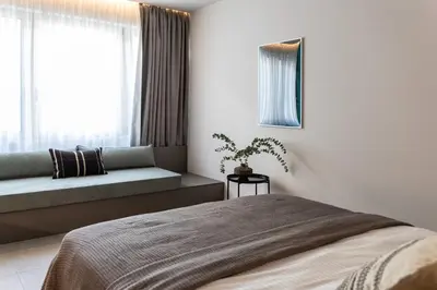 a bedroom with a bed and a couch and a window at Celestial Athens Suites at Praxitelous in Athens