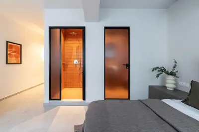 a bedroom with a bed and a wooden door at Celestial Athens Suites at Praxitelous in Athens