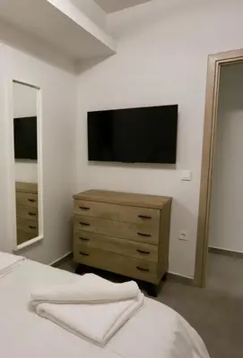 a bedroom with a tv on the wall and a dresser at Elaion guest house in Athens