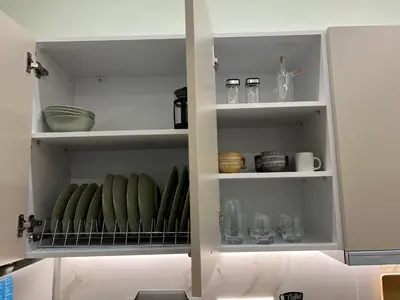 a white cabinet with green bowls and dishes in it at Cozy and modern apartment in Athens