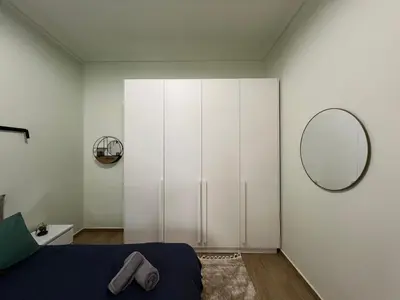 a bedroom with a large white wardrobe and a mirror at Cozy and modern apartment in Athens