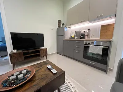 a kitchen with a tv and a table in a room at Cozy and modern apartment in Athens
