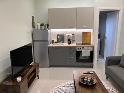 a kitchen with a refrigerator and a table in a living room at Cozy and modern apartment in Athens