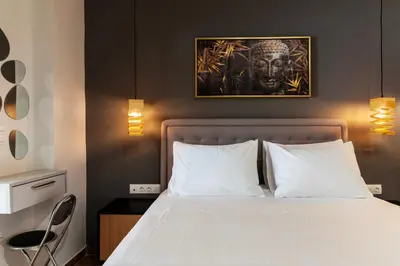 a bedroom with a white bed with a portrait on the wall at Luxury Boutique Suite w Balcony 5 min Metro in Athens