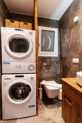 a bathroom with a washing machine and a tv at Luxury Boutique Suite w Balcony 5 min Metro in Athens