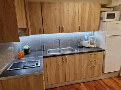 a kitchen with wooden cabinets and a sink and a refrigerator at AIOLOU st - 2 BDR APT - NetFlix in Athens