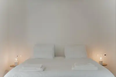 a white bed with two white towels on it at Beach Bliss Studio in Athens