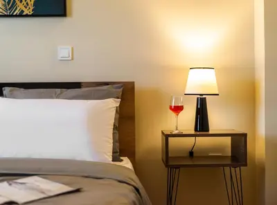 a bed with a lamp and a glass of wine on a night stand at Spacious Rooftop Apt in Central Athens with Sunset Balcony in Athens
