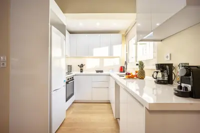 a white kitchen with white cabinets and appliances at Spacious Rooftop Apt in Central Athens with Sunset Balcony in Athens