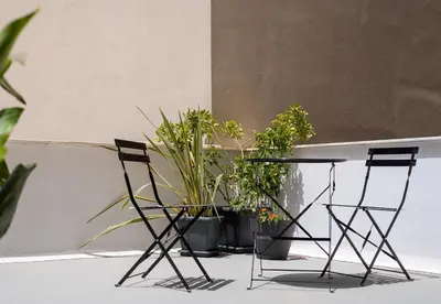 two chairs and a table with plants in front of a wall at Stylish Escape Suite in Athens in Athens