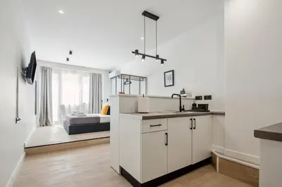 a white kitchen with a sink and a bedroom at Exquisite Athens Center Suite in Athens