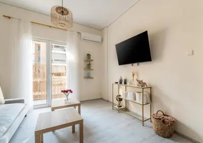 a living room with a couch and a tv on the wall at Emilia Athens in Athens