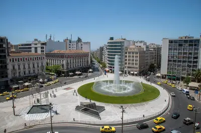 a fountain in the middle of a city with cars at Athens Central Stay, 3BD Apartment, 3min Metro in Athens
