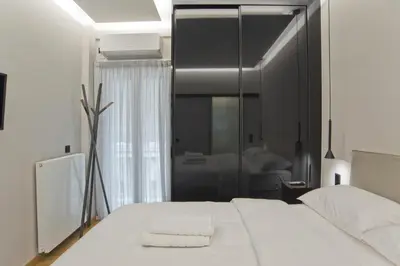a bedroom with a large white bed with a mirror at Stylish Ilisia Stay Luxury Fully Reno 2BR, 2BA Apt in Athens