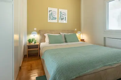 a bedroom with a bed with green sheets and a window at Almost A Penthouse But Better W Acropolis Glimpse in Athens