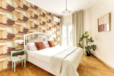 a bedroom with a large white bed with a geometric wall at Quiet 1br Home Near Plaka & Acropolis in Athens