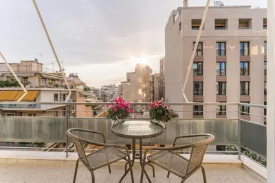 a table with chairs and flowers on a balcony at Spacious 3br Home Near Acropolis Museum in Athens