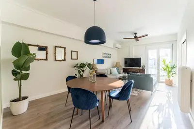 a living room with a wooden table and blue chairs at Spacious 3br Home Near Acropolis Museum in Athens