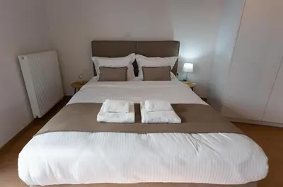 a large white bed with two towels on it at Cozy apartment in Koukaki in Athens