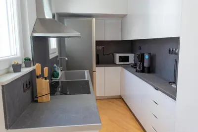 a kitchen with white cabinets and a gray counter top at Cozy apartment in Koukaki in Athens
