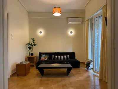a living room with a black couch and a window at Cozy place at the center of Athens in Athens