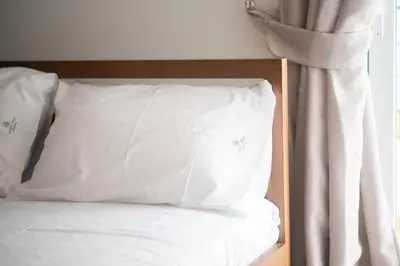 a bed with white sheets and pillows next to a window at Spacious Family Apt in Glyfada in Athens