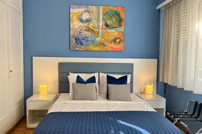 a blue bedroom with a bed and a painting on the wall at Phaedrus Living Kolonaki Blue in Athens