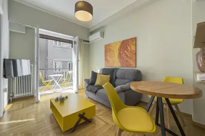 a living room with a couch and a table and yellow chairs at Phaedrus Living Kolonaki Blue in Athens