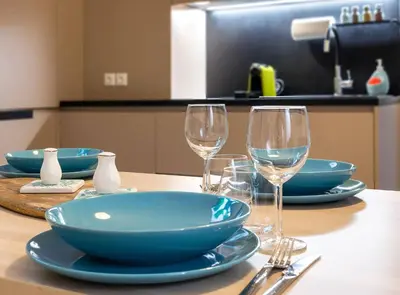 a table with blue plates and wine glasses on it at 2 Bedroom Apt with Secret Garden In The heart Of Athens in Athens