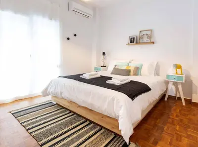 a bedroom with a large white bed with a rug at 2 Bedroom Apt with Secret Garden In The heart Of Athens in Athens