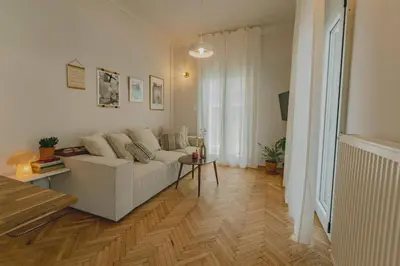 a living room with a white couch and a wooden floor at Stylish cozy artistic Athens apartment in Athens