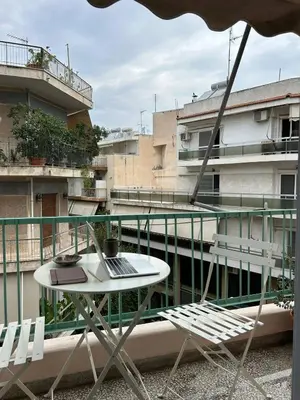 a table and chairs on a balcony with a building at Stylish cozy artistic Athens apartment in Athens