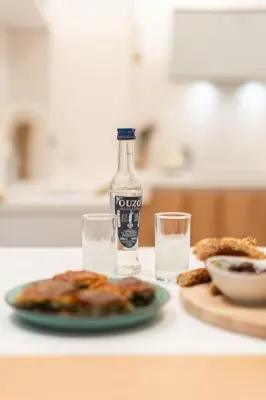 a bottle of water next to a plate of food and glasses at My Happy Greek Home in Athens